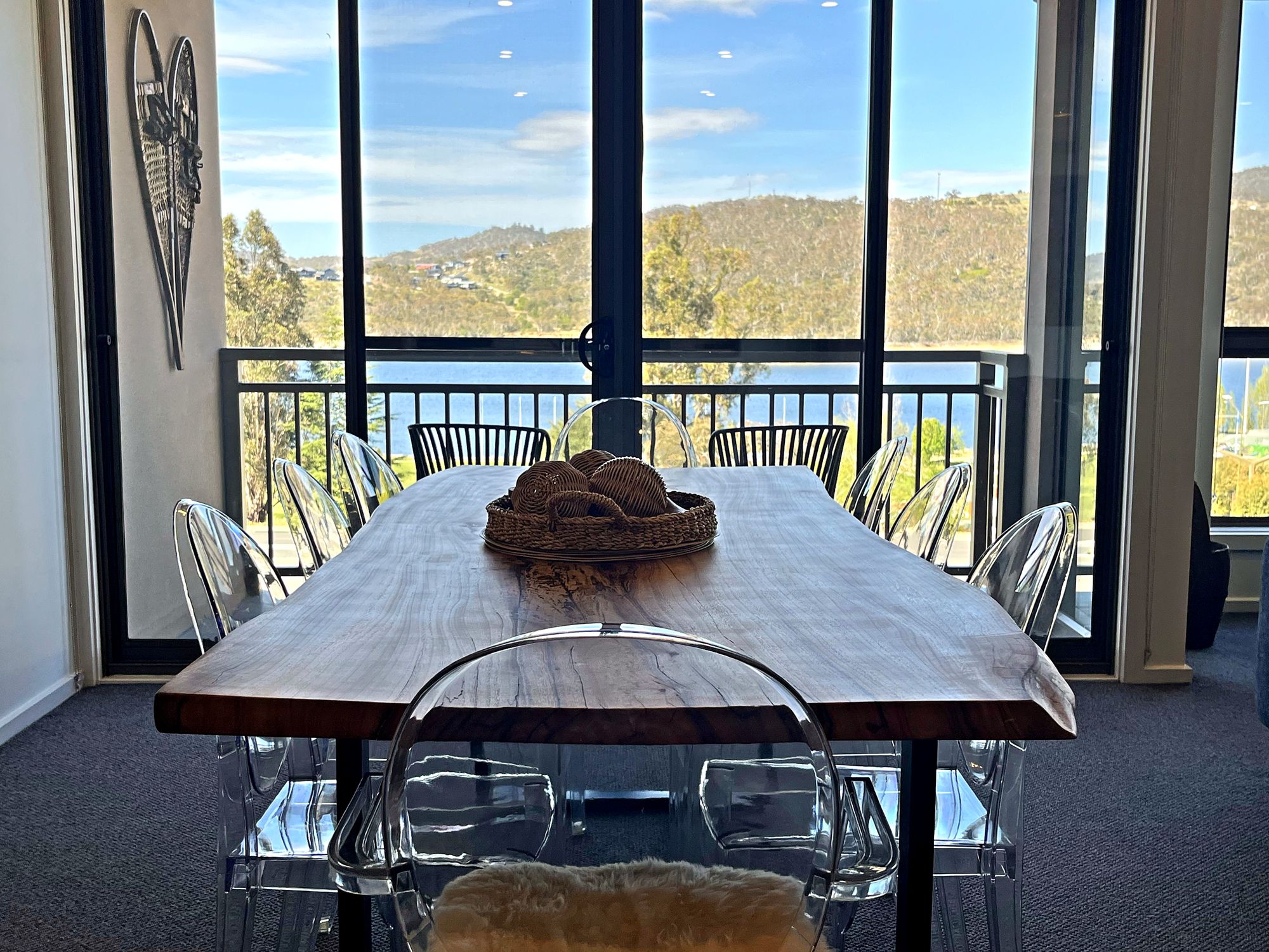 Live-edge dining table in front of floor-to-ceiling windows looking over Lake Jindabyne