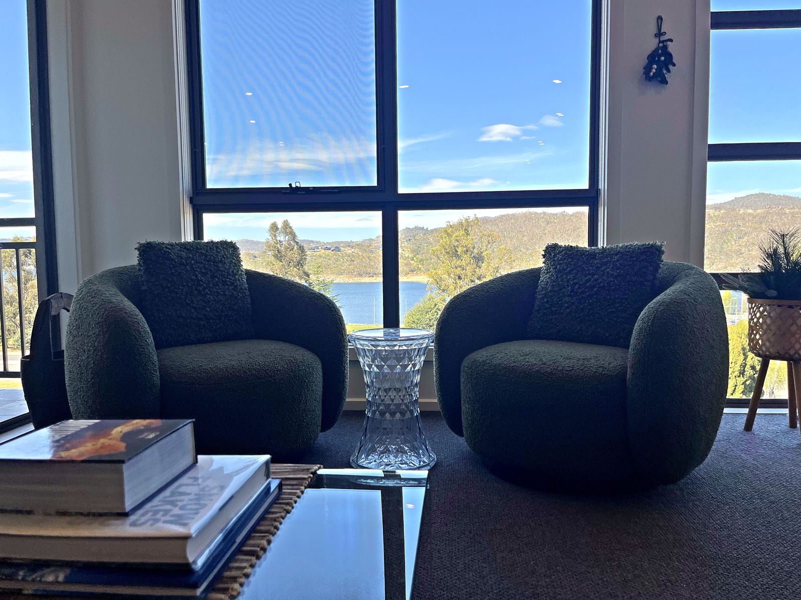 Two armchairs facing floor-to-ceiling windows over Lake Jindabyne
